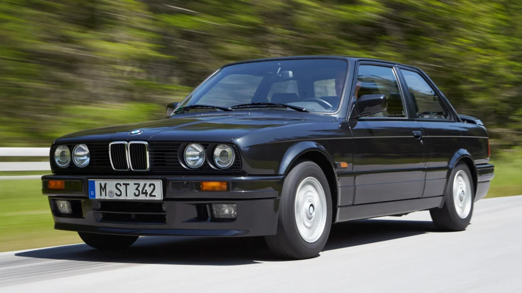 a high-resolution, detailed image of the interior of an original BMW E30 sedan, showcasing its classic and elegant design. The scene should be well-lit, capturing the warm, luxurious atmosphere of the cabin. Prominently feature the dashboard, with its analog gauges and sleek, minimalist controls. Emphasize the driver-centric layout, with the steering wheel, gear shifter, and center console in focus. Render the rich, supple leather upholstery, the solid wood accents, and the carefully crafted door panels in vivid detail. Include the front seats, as well as a glimpse of the rear seats, to convey the spacious and comfortable nature of the E30's interior. The image should have a realistic, photographic quality, highlighting the timeless design and premium craftsmanship that define the BMW E30's iconic cabin.